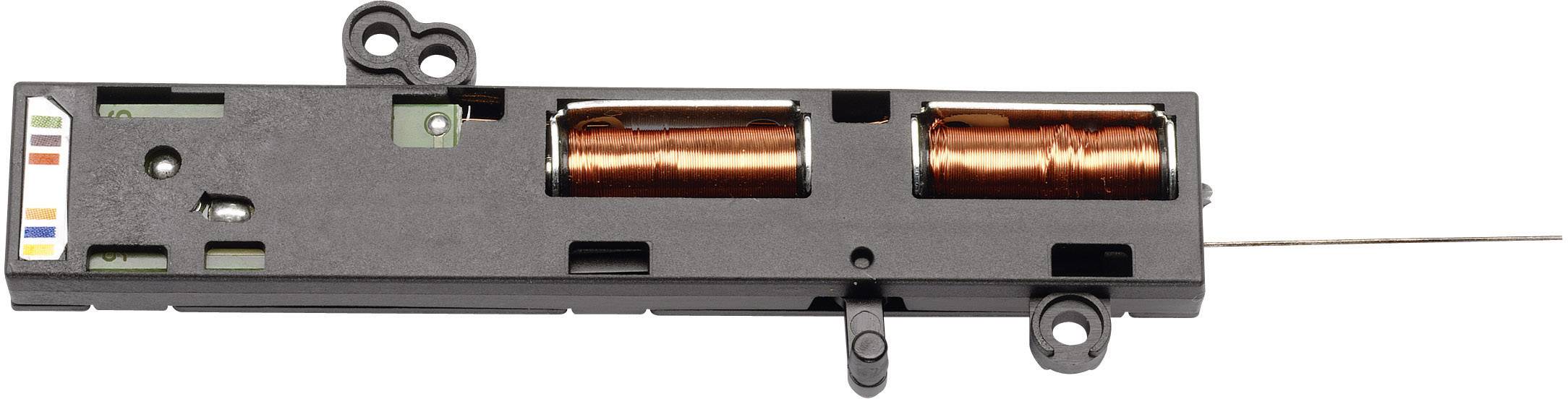 Bobina elettronica in un contenitore nero con due avvolgimenti in rame visibili, probabilmente un componente di un dispositivo tecnico.