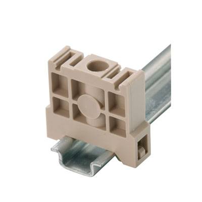Un supporto beige in plastica è montato su una guida metallica e serve per fissare componenti elettrici negli armadi elettrici.