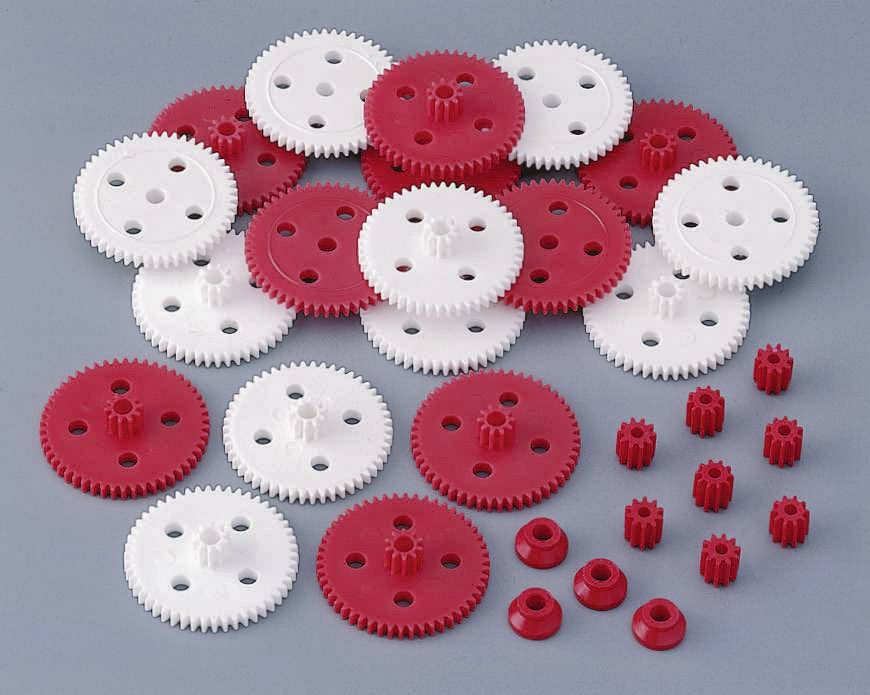 Ingranaggi rossi e bianchi di diverse dimensioni su sfondo grigio, disposti in un gruppo.