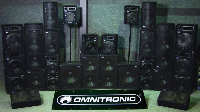 Una raccolta di altoparlanti neri di varie dimensioni del marchio 'Omnitronic', disposti simmetricamente davanti a una parete.