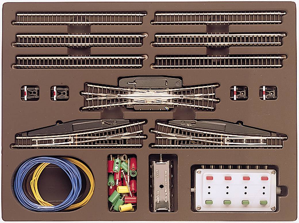 Set di accessori per modellismo ferroviario con binari, scambi, cavi colorati, interruttori e pannello di controllo in confezione aperta.