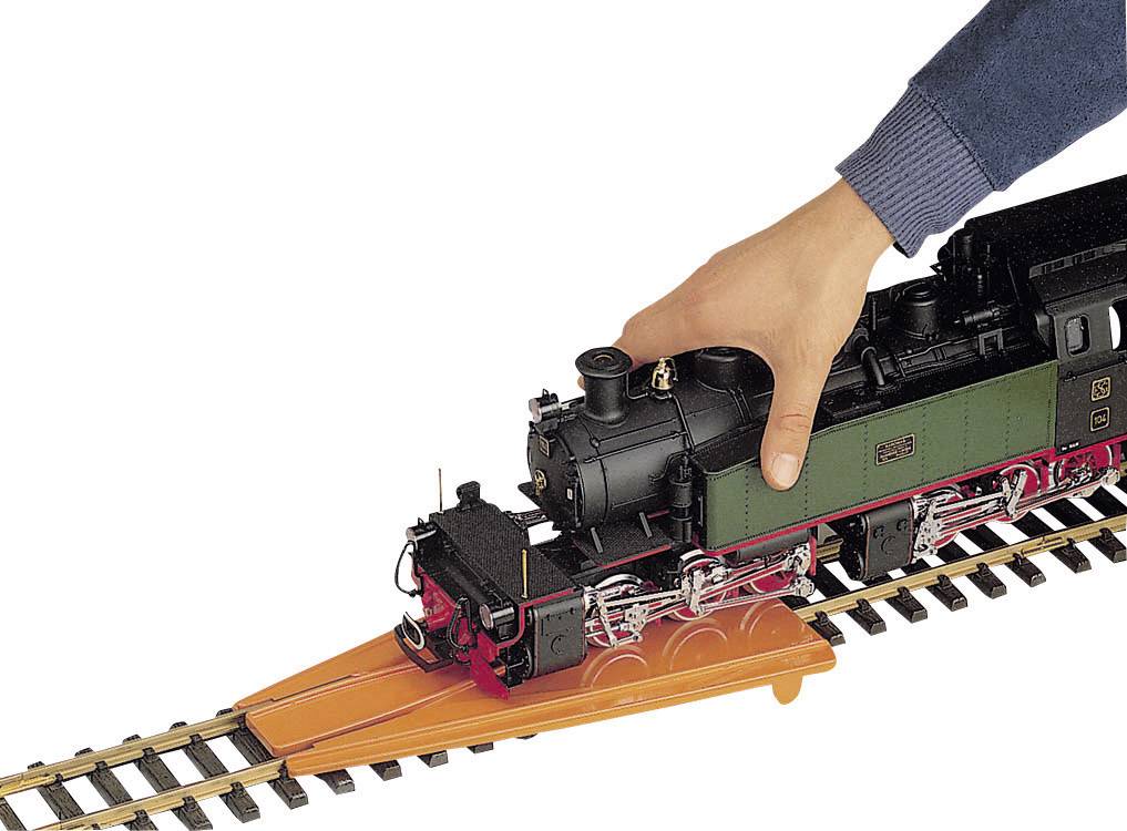 Una mano posiziona una locomotiva modello sui binari con l'aiuto di una rampa ferroviaria.