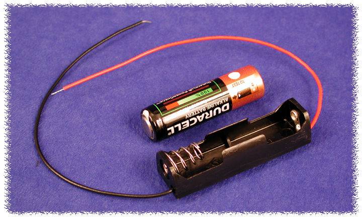 Portabatterie con una batteria Duracell rimossa e due cavi in uscita, uno rosso e uno nero, su sfondo blu.
