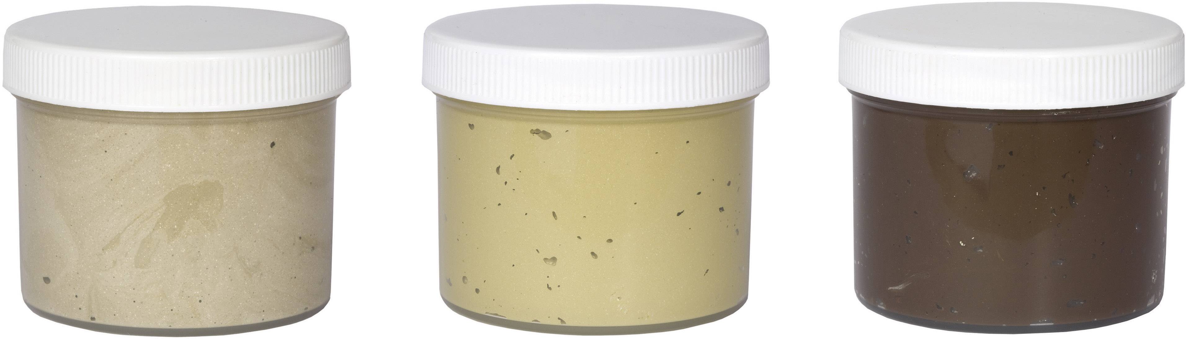 Tre barattoli con coperchi a vite, riempiti da sinistra a destra con pasta beige, gialla e marrone.