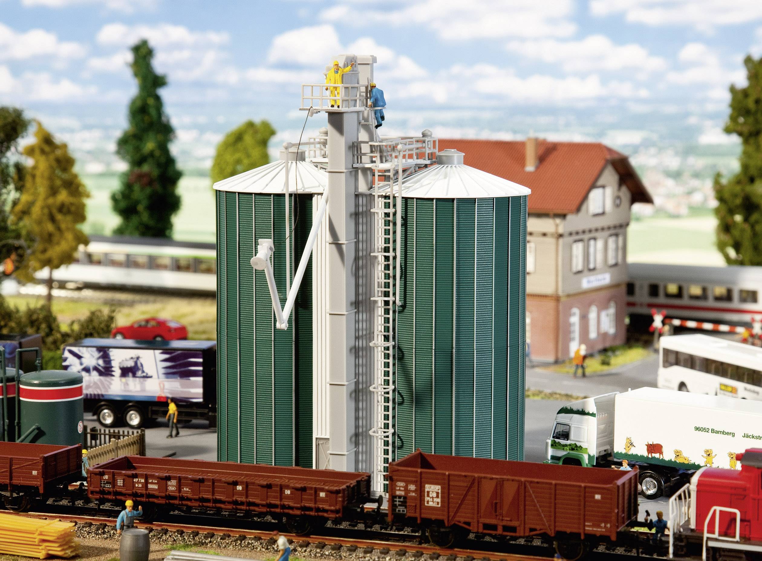 Un modello di una scena con silos di cereali, treni e una casa sullo sfondo. Si vedono lavoratori occupati intorno ai silos.