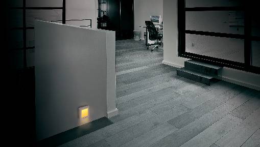 Un ufficio con una scrivania sullo sfondo. In primo piano, un piccolo interruttore illumina la parete.