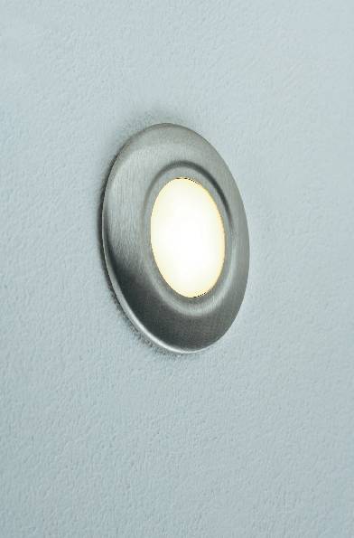 Un'apertura circolare di un obiettivo fotografico metallico su una superficie nera con uno sfondo azzurro chiaro.