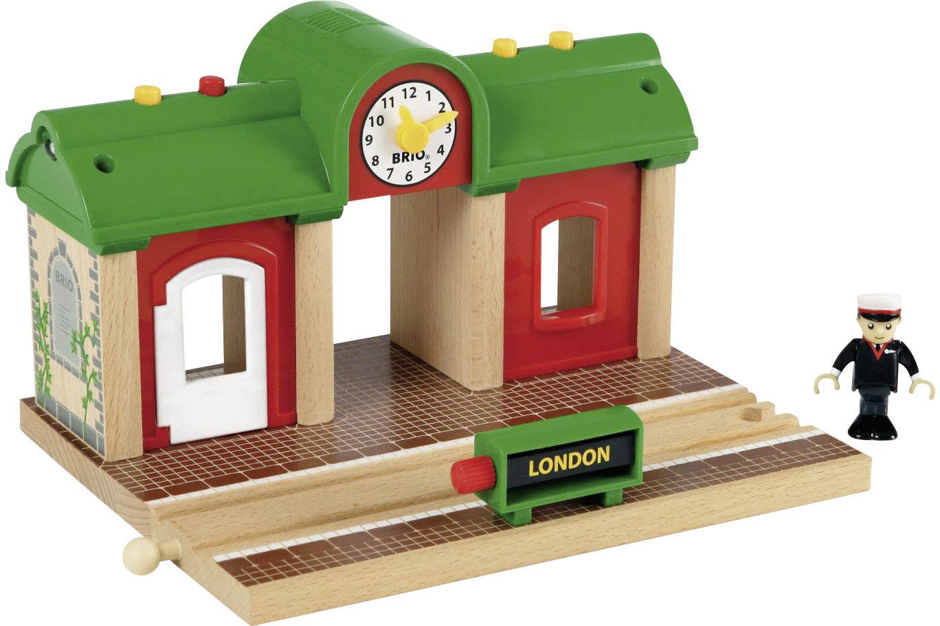 Stazione giocattolo in legno con orologio e tetto verde. Sul cartello è scritto 'London'. Accanto è in piedi una pedina con una divisa.