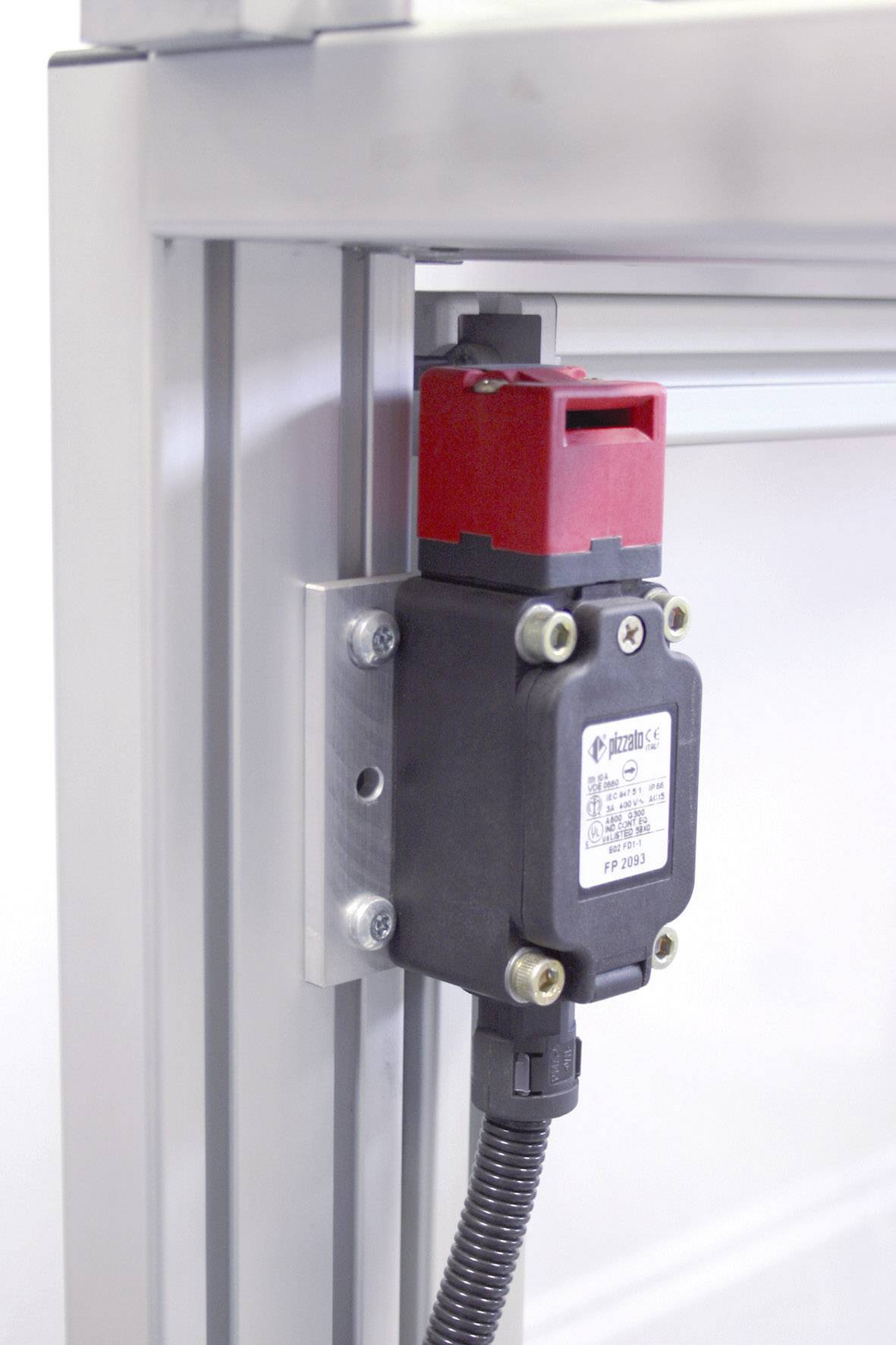 Un interruttore di sicurezza rosso è montato su una cornice metallica argentata. Si tratta di un interruttore elettrico con cavo.