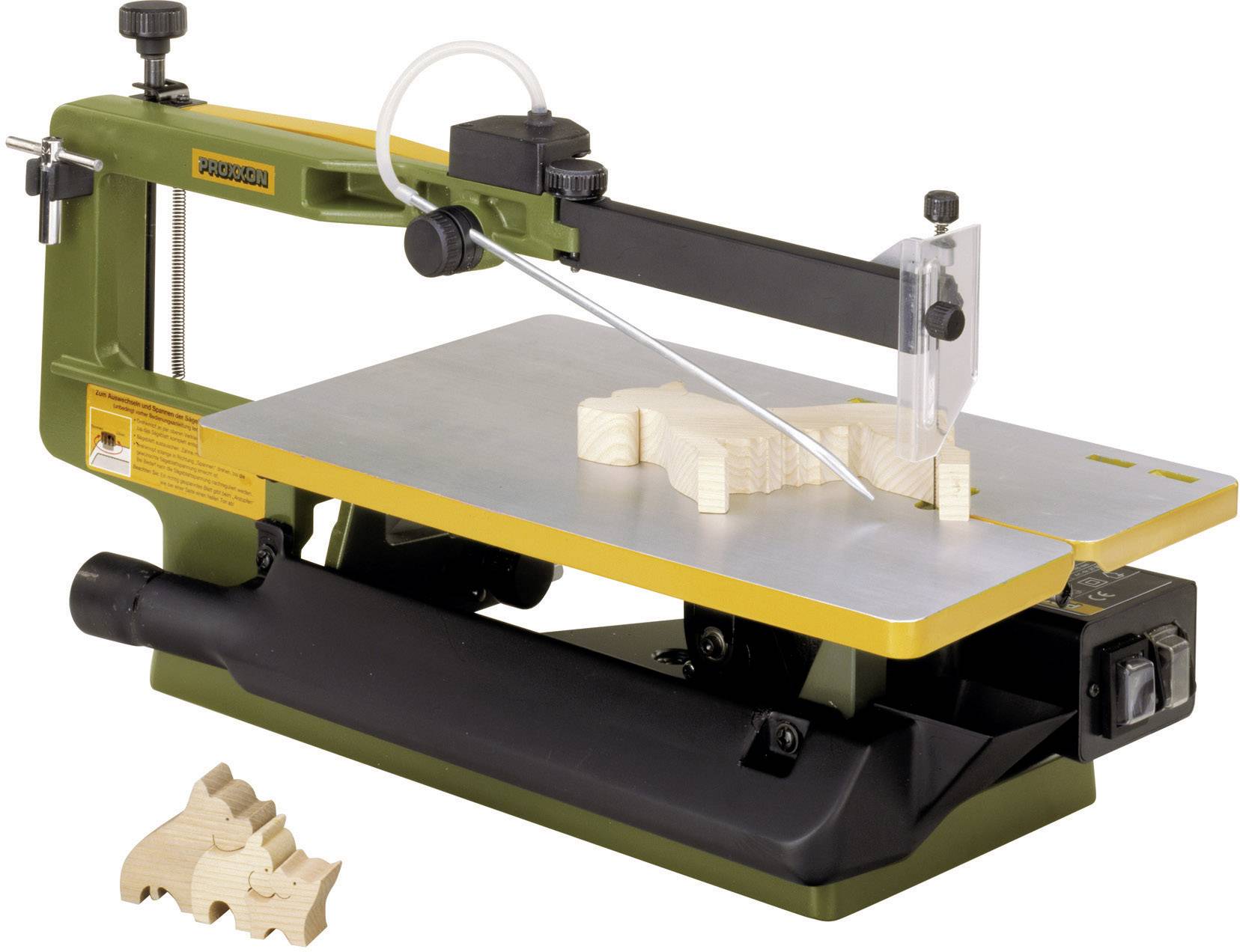 Una sega da traforo taglia una sagoma di legno a forma di animale. Accanto ci sono pezzi di legno già pronti a forma di dinosauri.