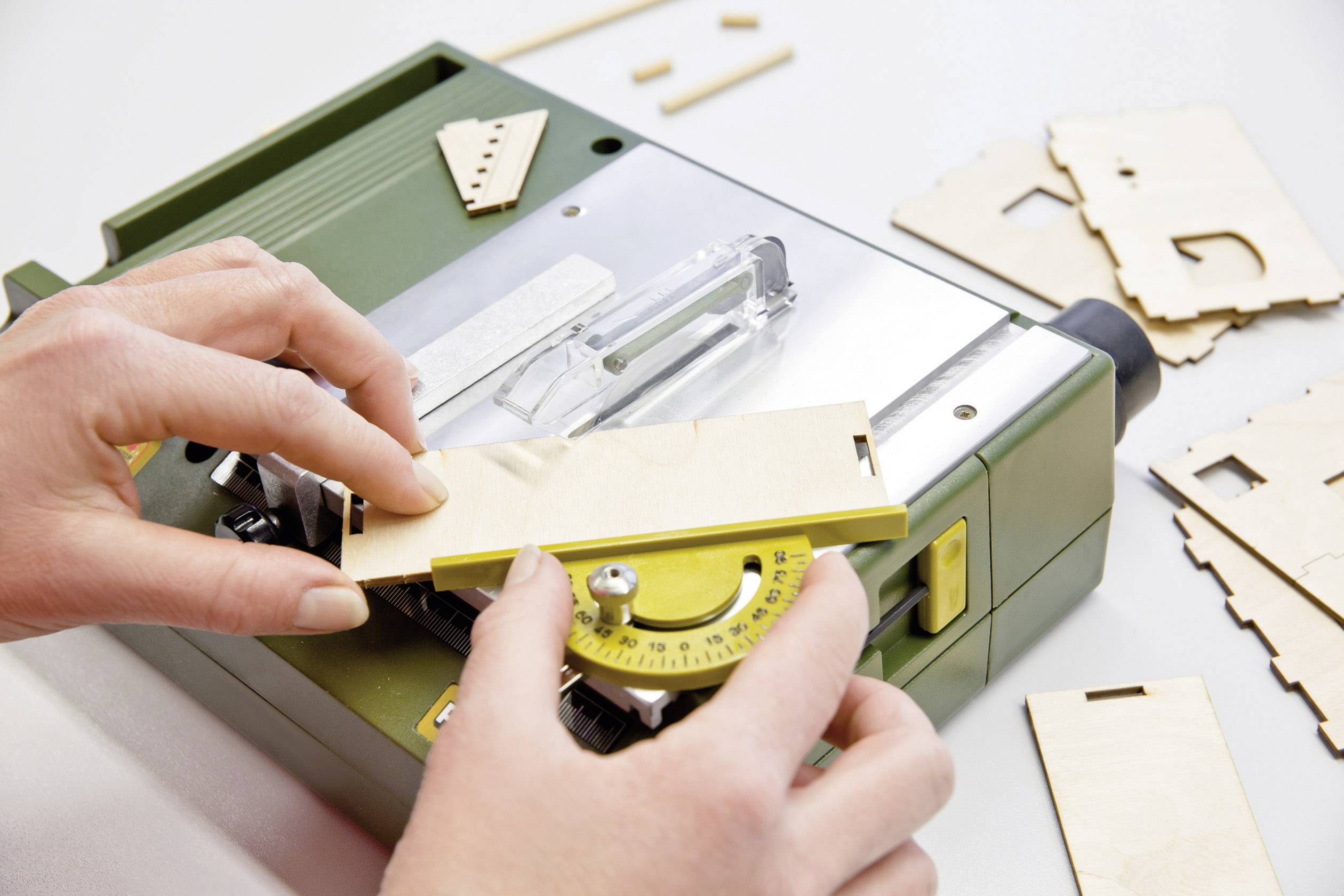 Una persona sta regolando un goniometro geodetico su una sega da traforo e sta preparando pezzi di legno per il taglio.