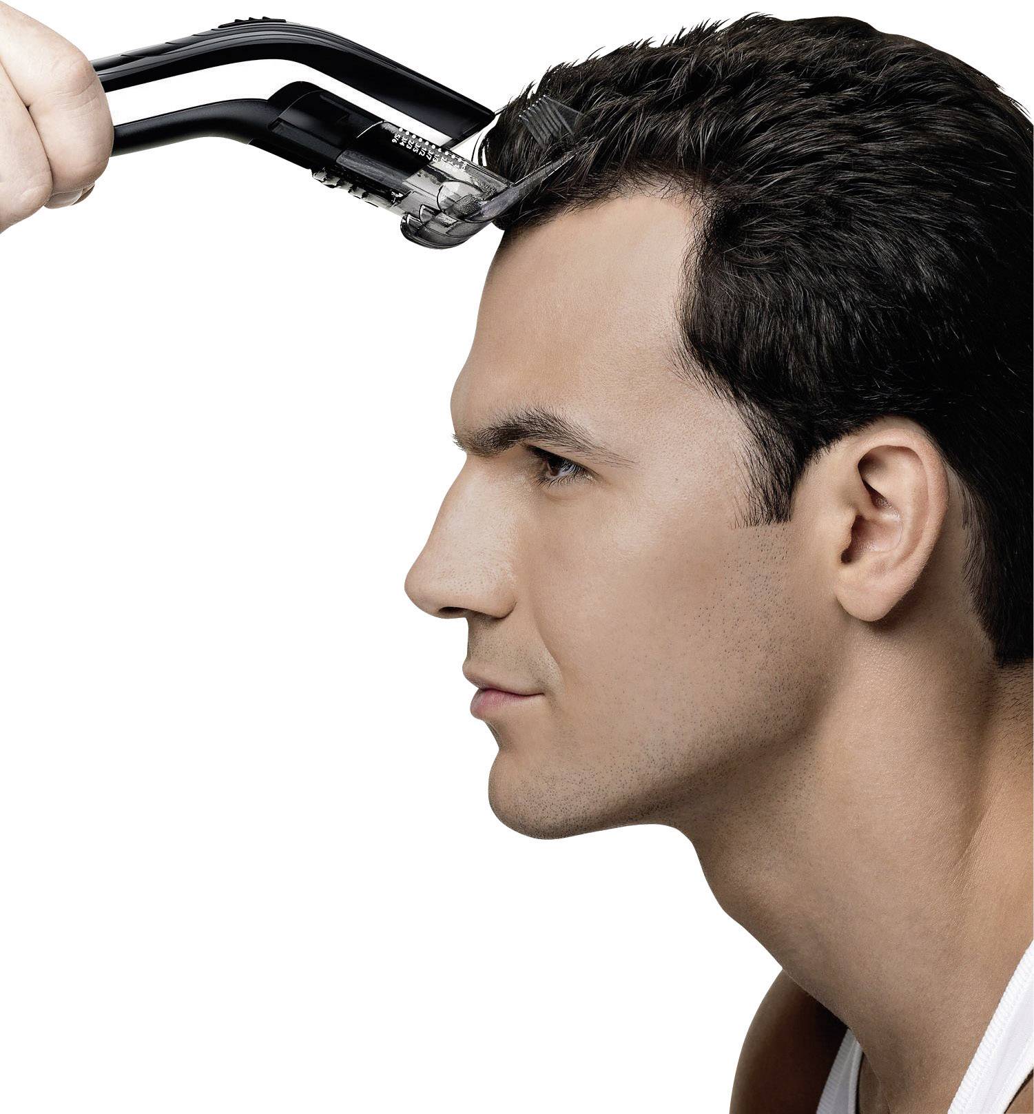Un uomo è ripreso di lato mentre si taglia i capelli con un tosacapelli elettrico.