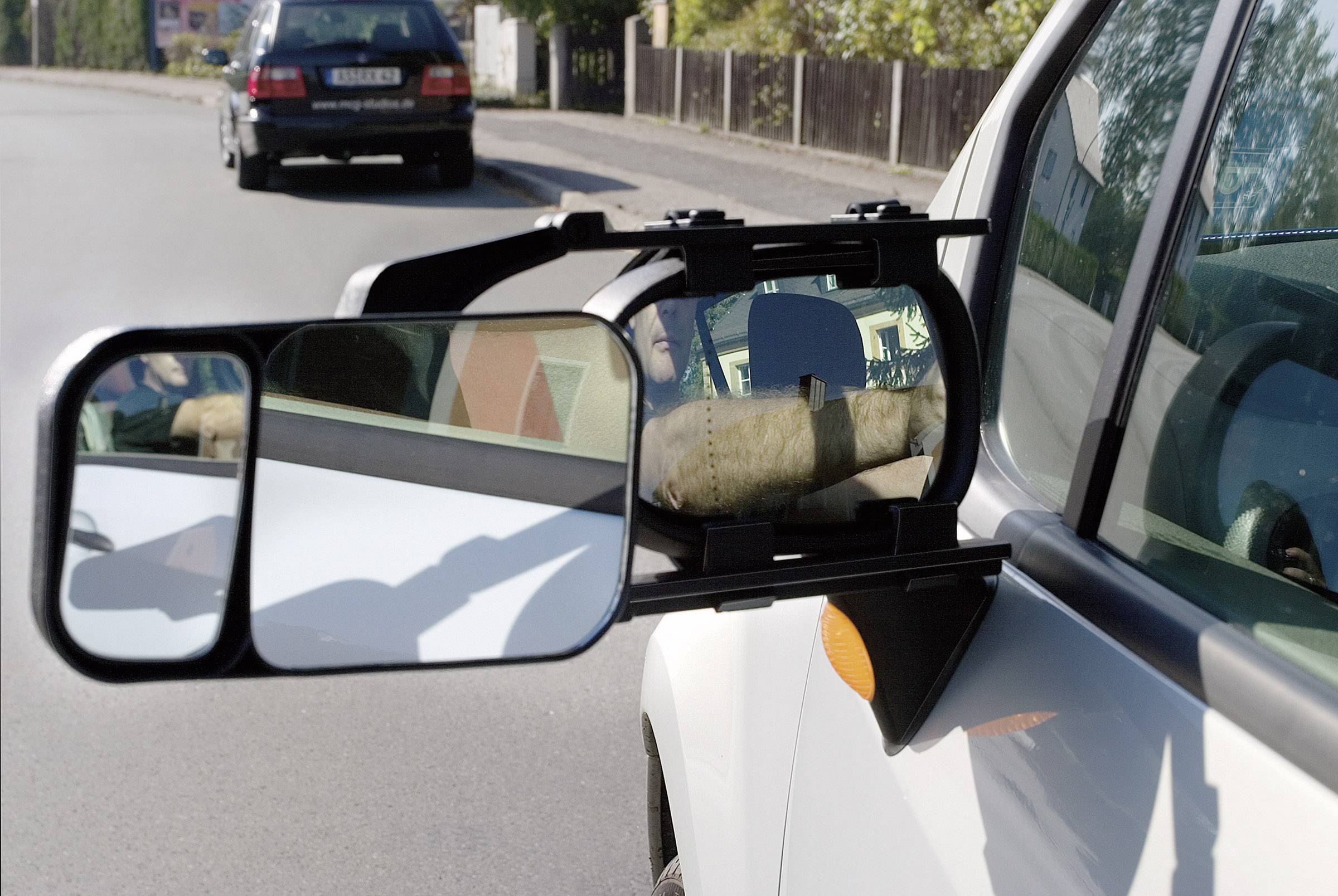 Un camper con uno specchio esterno aggiuntivo sta percorrendo una strada. Un'auto lo sta seguendo.