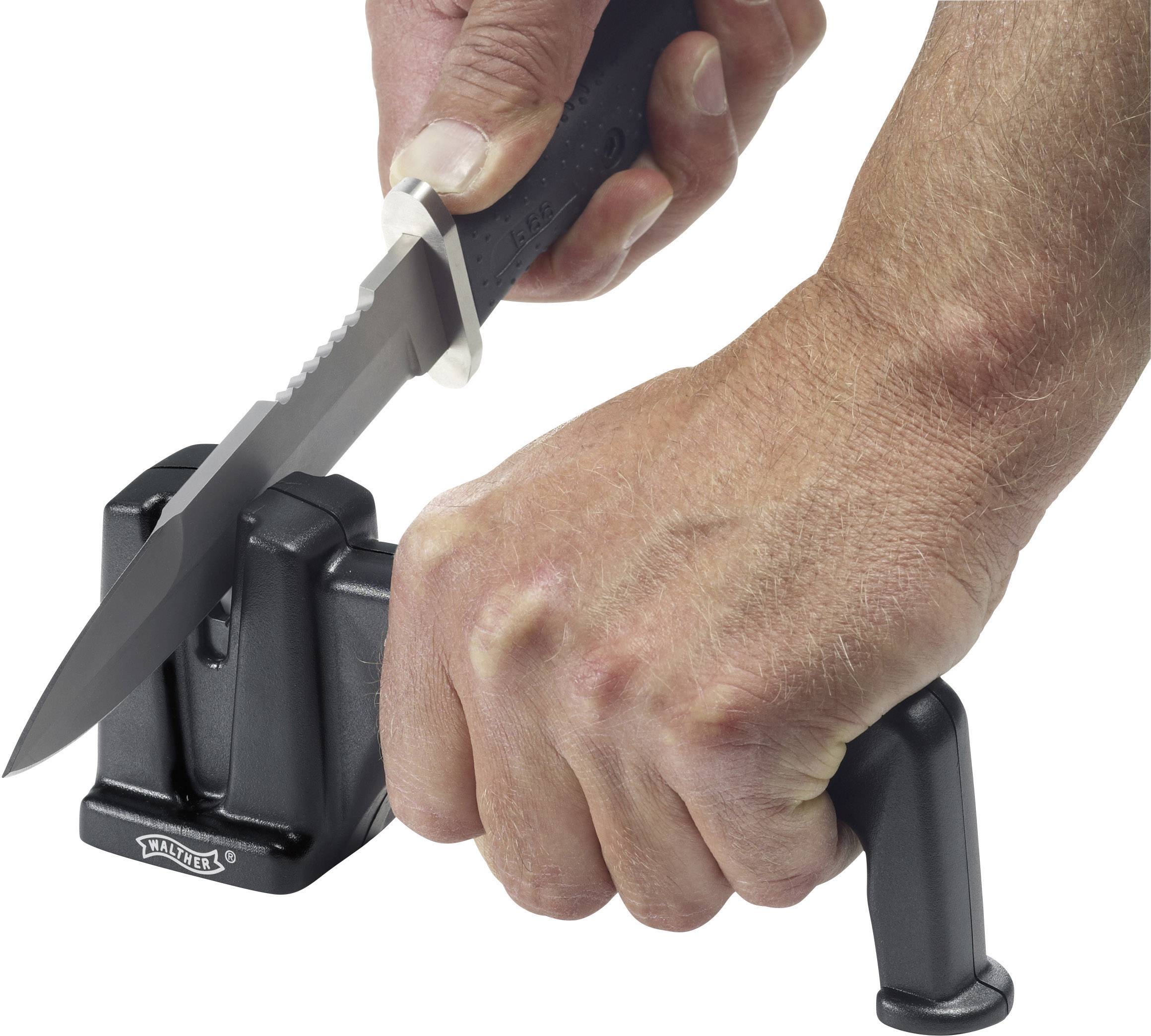 Un coltello viene tenuto in un dispositivo per affilare con una mano, mentre l'altra mano stabilizza l'attrezzo.