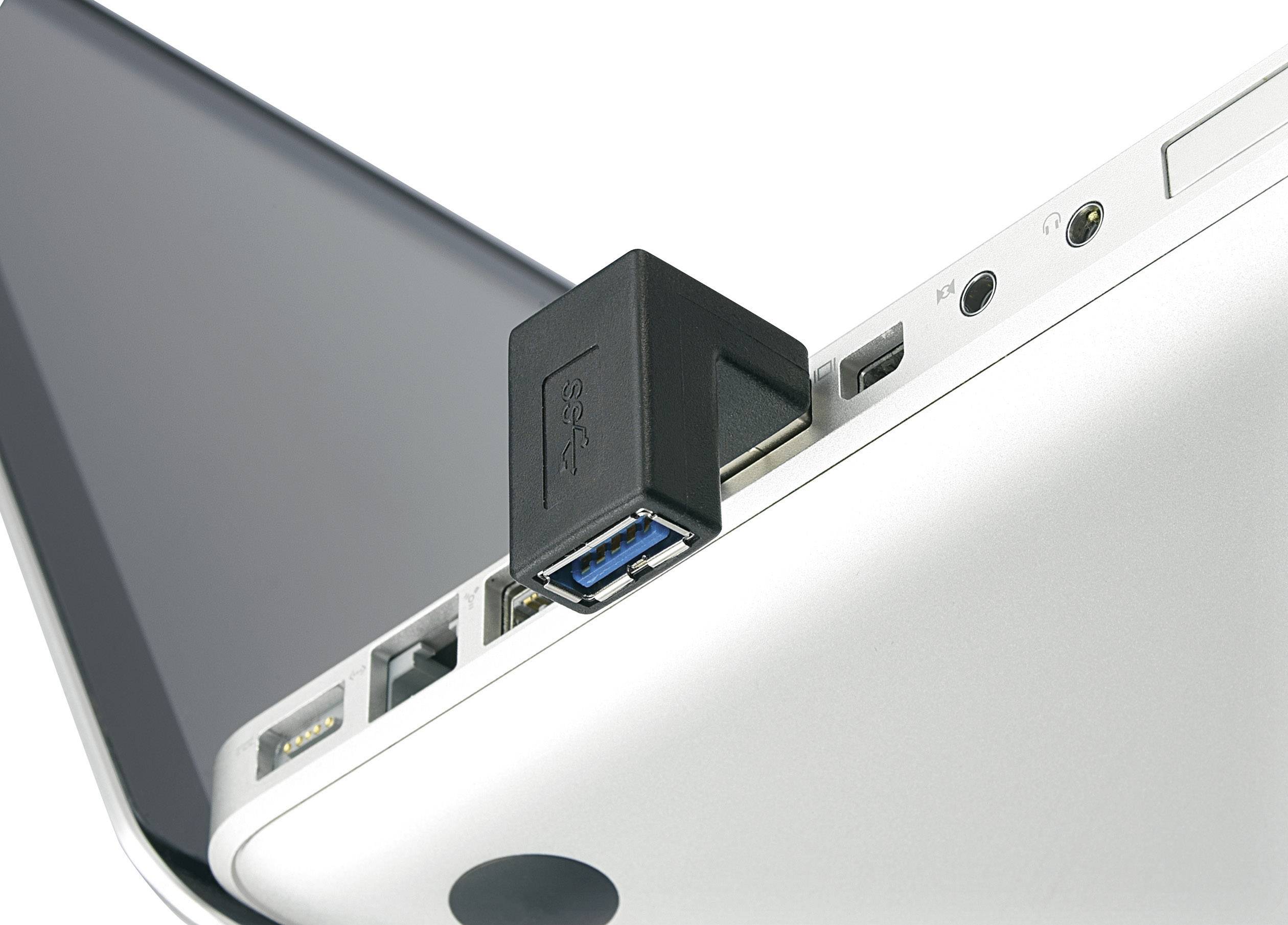 Un connettore USB nero è inserito nella porta USB di un laptop argentato. Il laptop è parzialmente aperto.