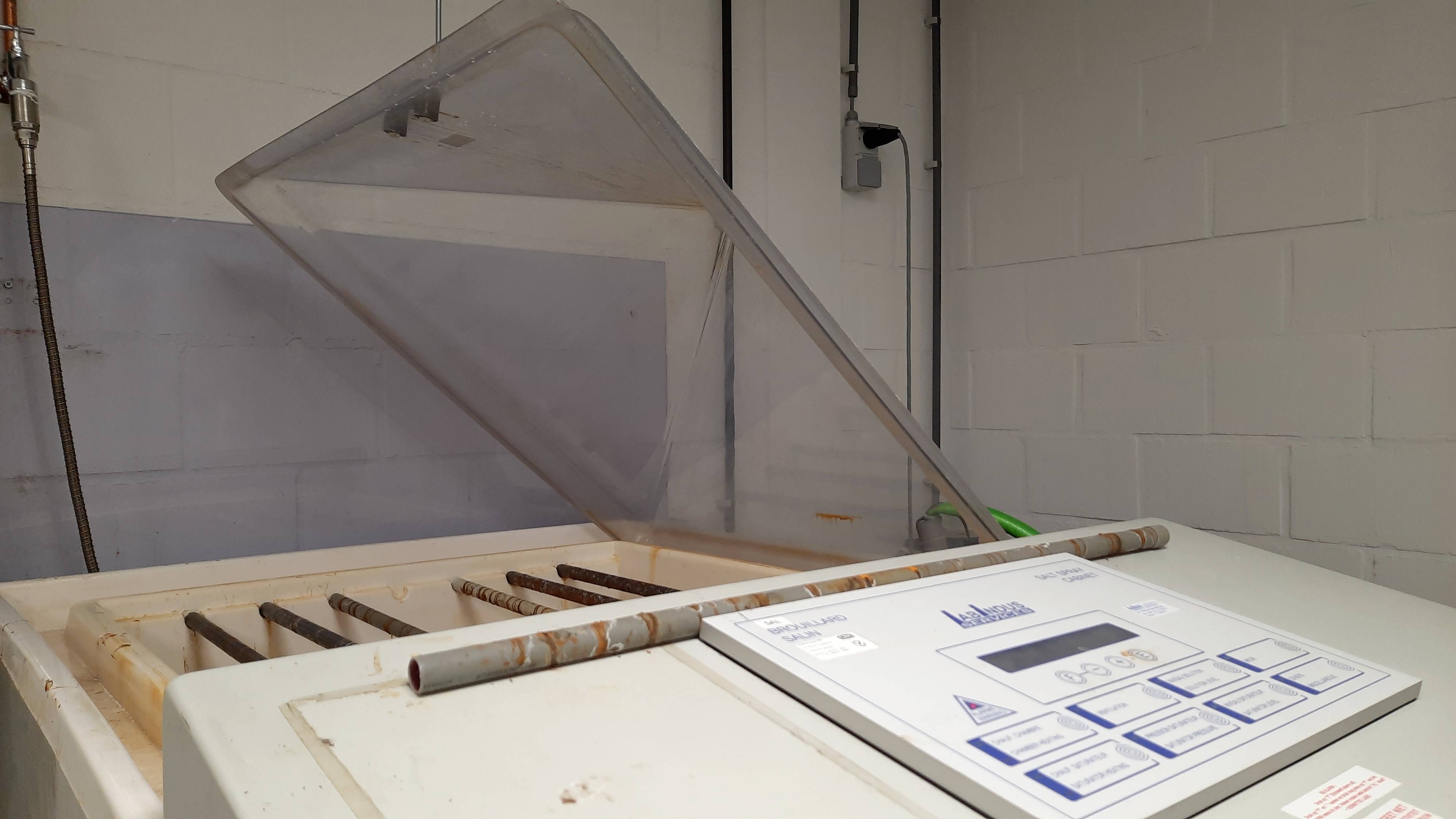 Afbeelding van een open laborapparaat met een gekantelde transparante deksel. Het toont een bedieningspaneel met knoppen en een digitaal display.