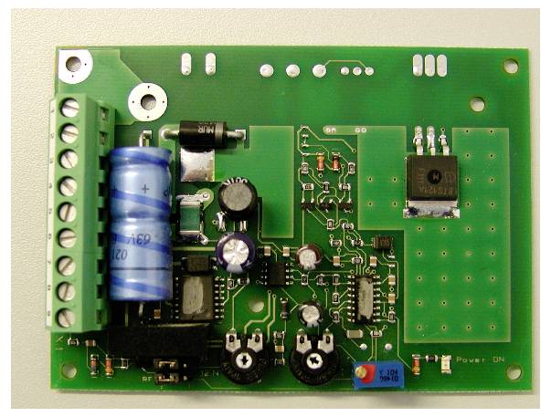 Een printplaat met verschillende elektronische componenten zoals condensatoren, weerstanden en een microchip; onderdeel van een elektronisch apparaat.