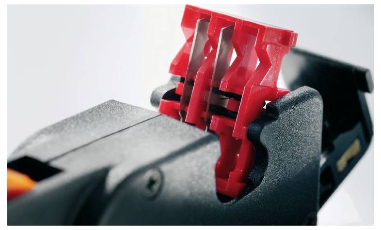 Close-upfoto van een zwart mechanisch gereedschap met rode componenten. Mogelijk een handgereedschap voor kabelbewerking.