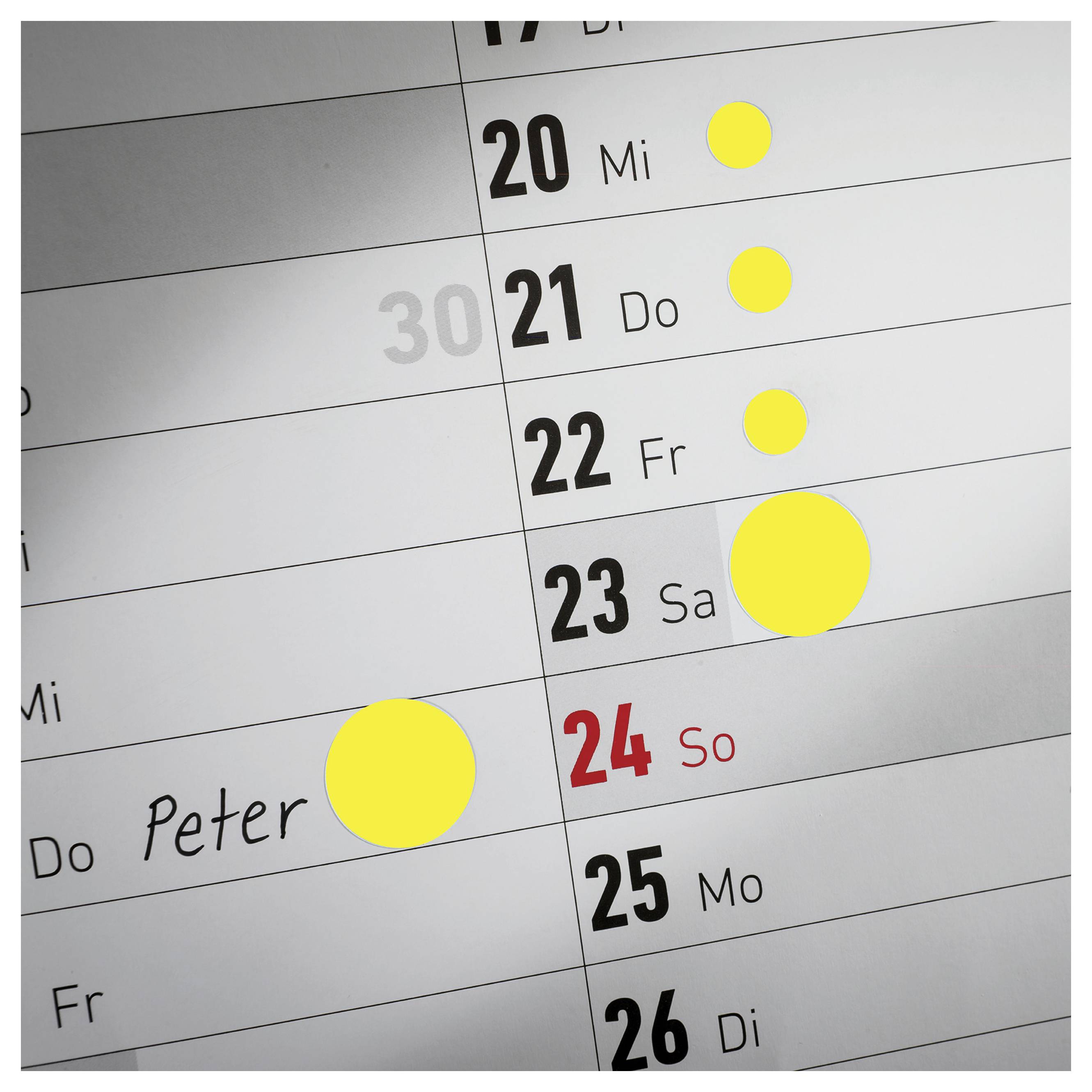 Nahaufname van een wandkalender met de dagen 20 tot 26; meerdere gele markeringen op de 20e, 21e, 22e, 23e en bij 'Peter' op 24 maart/dag 24.