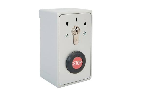 Noodstop-schakelaar in een grijze behuizing, met een rode knop gemarkeerd 'STOP', en een slot bovenaan om af te sluiten.