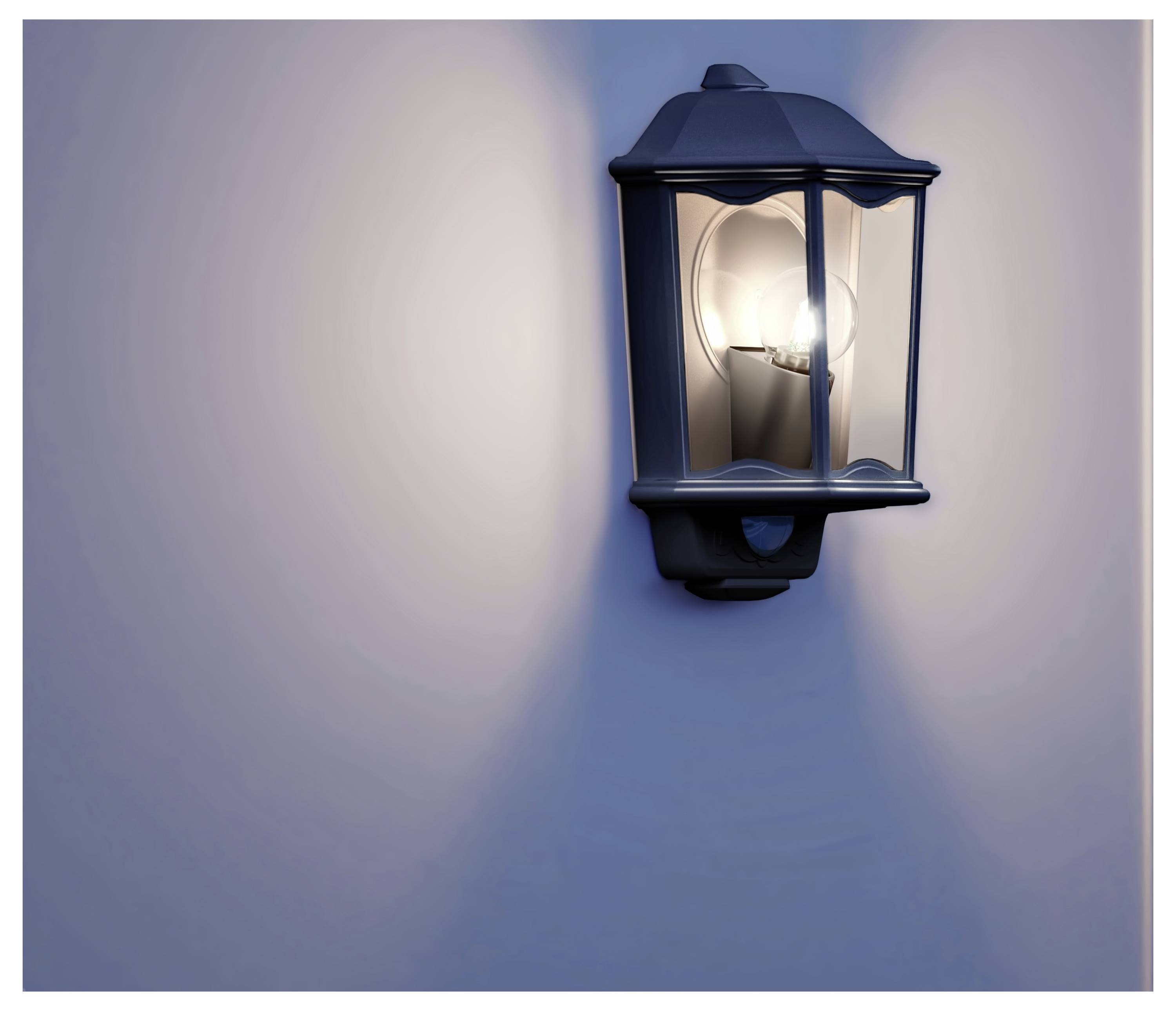 Verlichte buitenmuurlantaarn die zacht licht op een eenvoudige muur werpt.