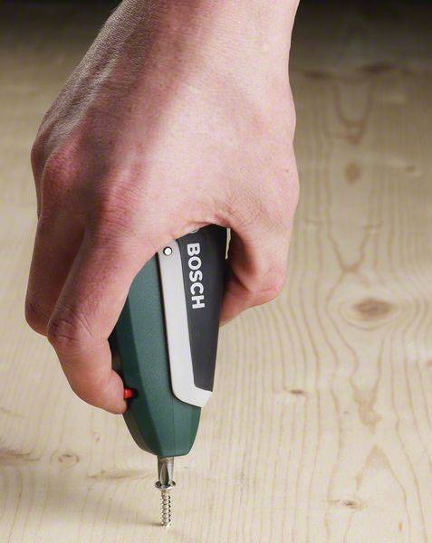 Een hand houdt een elektrische schroevendraaier van een bekend merk en draait een schroef in een houten plaat.