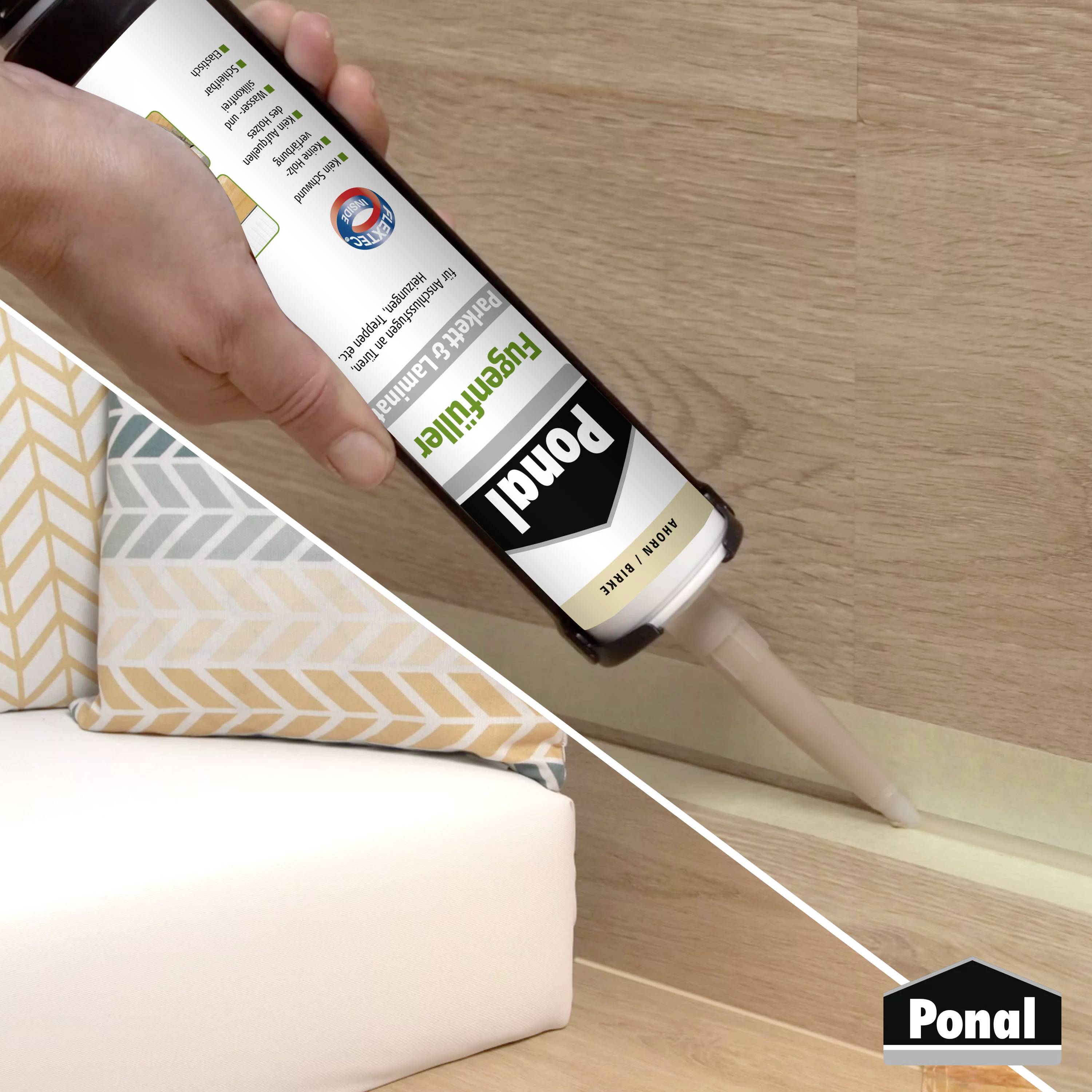 Een hand gebruikt een tube Ponal-lijm om een houten lat aan een houten vloer te bevestigen. Op de achtergrond zijn kussens zichtbaar.