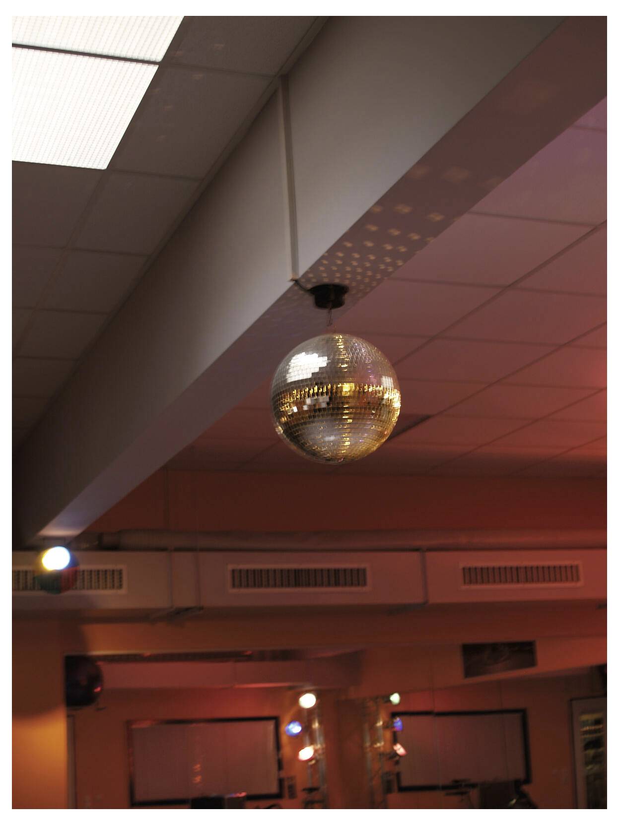 Discobal hangend aan een plafond in een zwak verlichte kamer met warm rood-oranje licht.