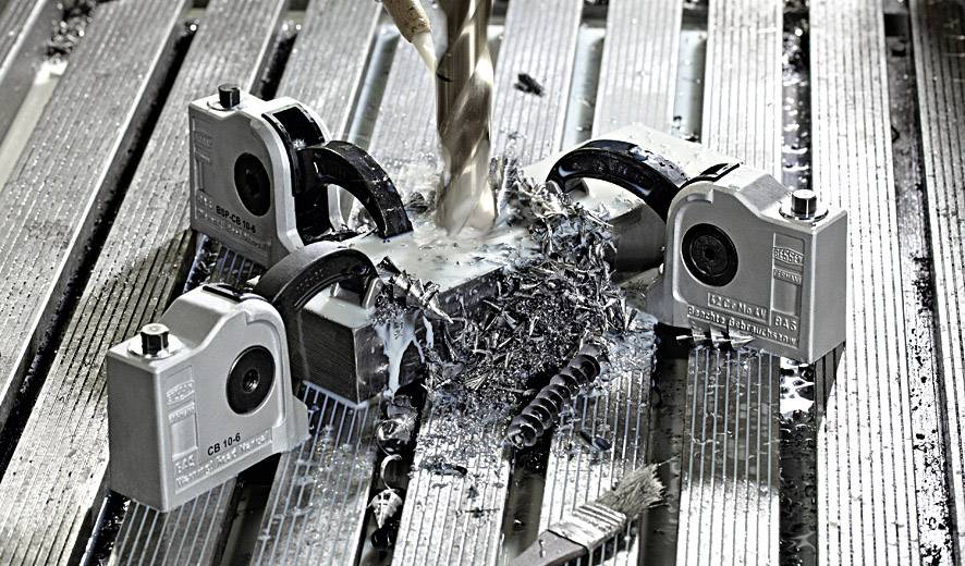 Boortoestel bewerkt metalen plaat omgeven door spanen. Meerdere spaninrichtingen houden het werkstuk stevig vast.