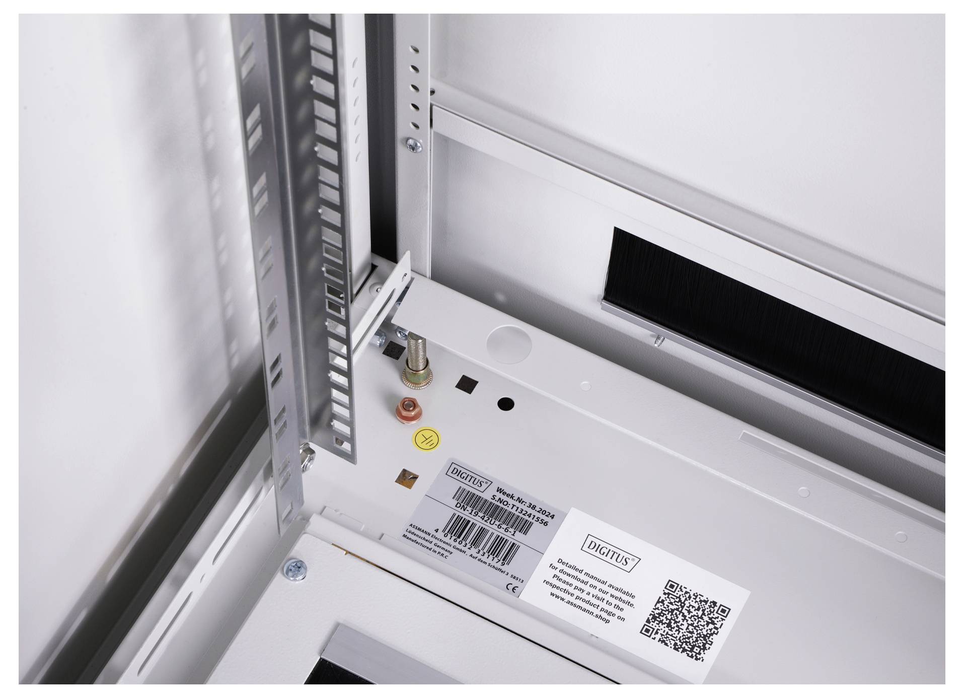 Binnenaanzicht van een elektronicabehuizing met schakelinstallatie-componenten en kabelaansluitingen. Een QR-code en diverse etiketten zijn zichtbaar.