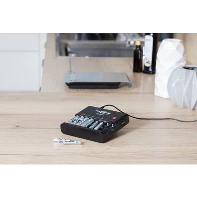 Oplader voor AA-batterijen op een houten tafel, waarbij meerdere batterijen tegelijkertijd worden opgeladen.