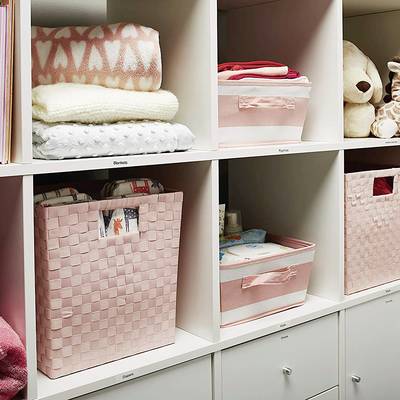Rek met roze opbergmanden en speelgoed. Netjes en decoratief gerangschikt, met kleding en knuffels.