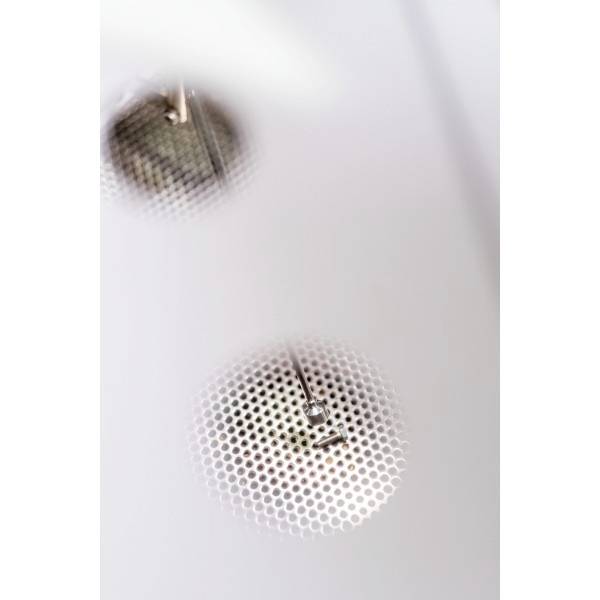 Een metalen structuur met een rond rooster dat licht in een ruimte weerkaatst.