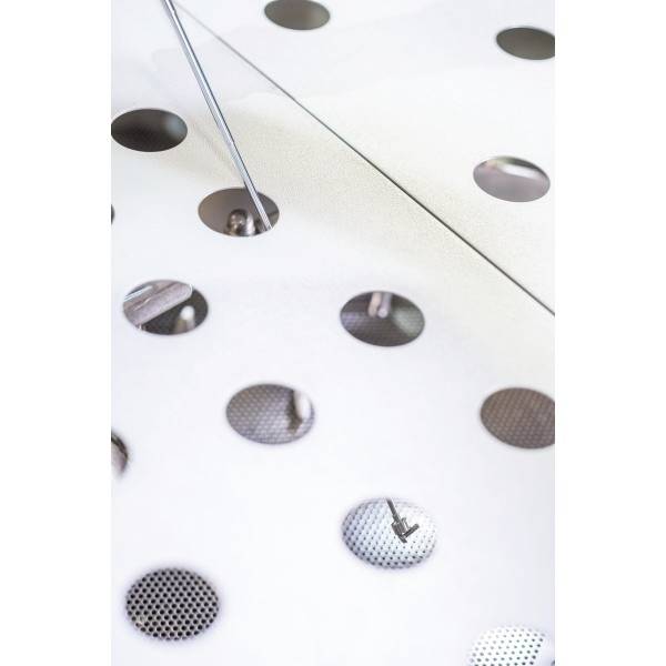 Een close-up van geperforeerd metaal met ronde openingen. Licht valt door de gaten en creëert een interessant patroon.