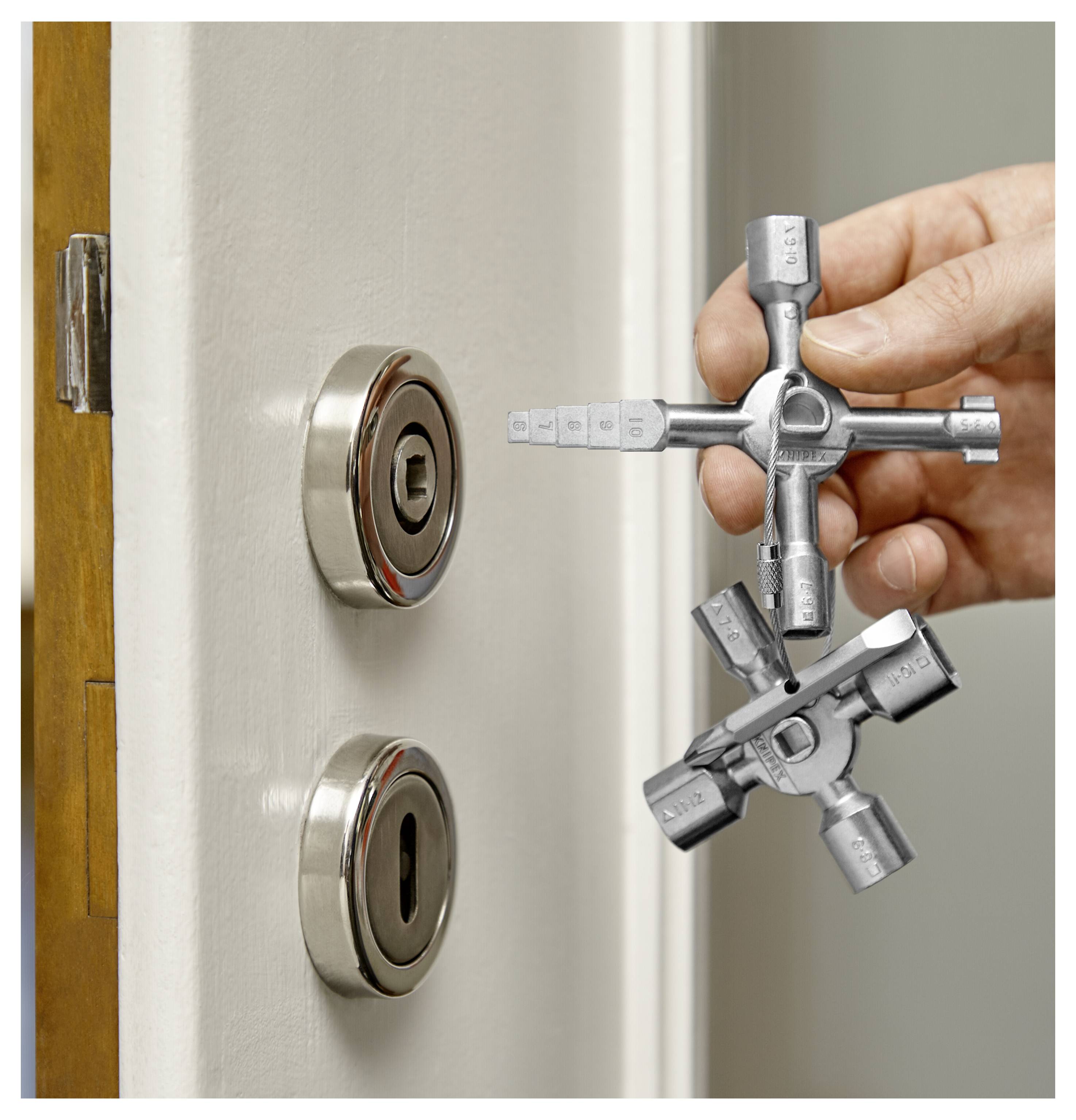 Een hand houdt een gereedschapssleutel vast naast een deur met twee ronde sloten, wat suggereert dat deze wordt gebruikt om de sloten te openen of te onderhouden.