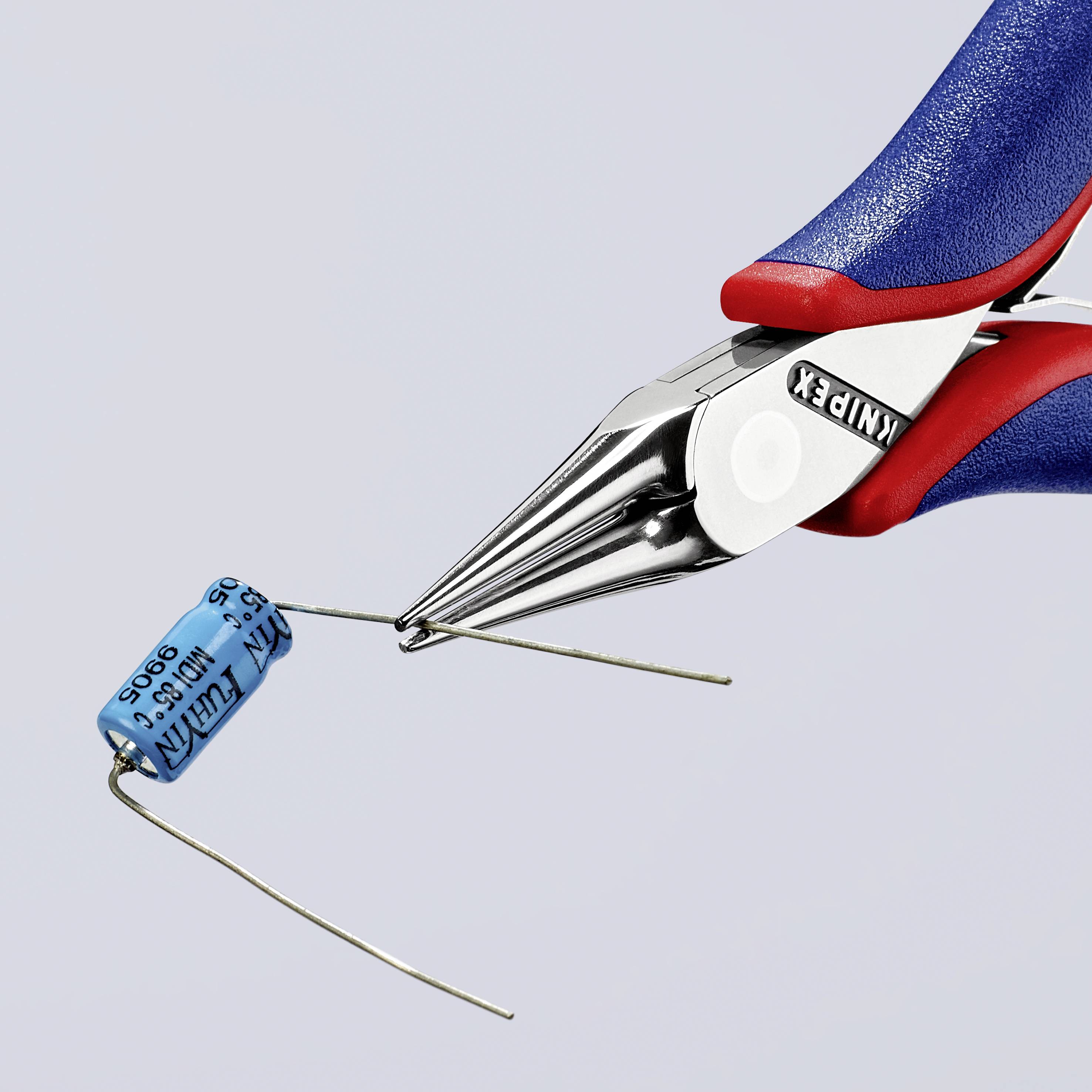 De afbeelding toont een Knipex-tang die een blauwe condensator vasthoudt en waarvan de draad wordt doorgeknipt.