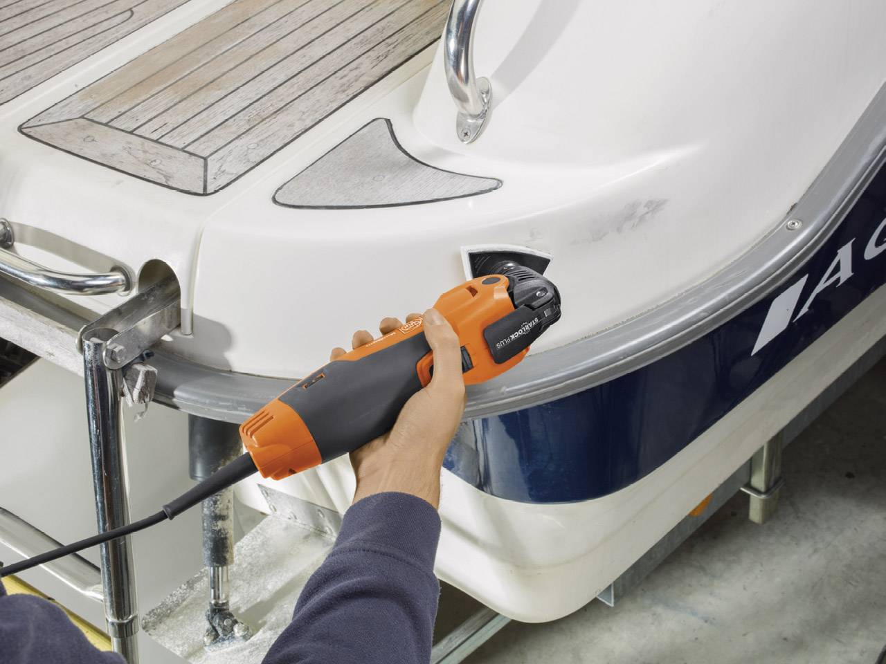 Een persoon bewerkt een boot met elektrisch gereedschap om krassen te verwijderen. Werkproces voor jachtonderhoud, met de focus op roestverwijdering.