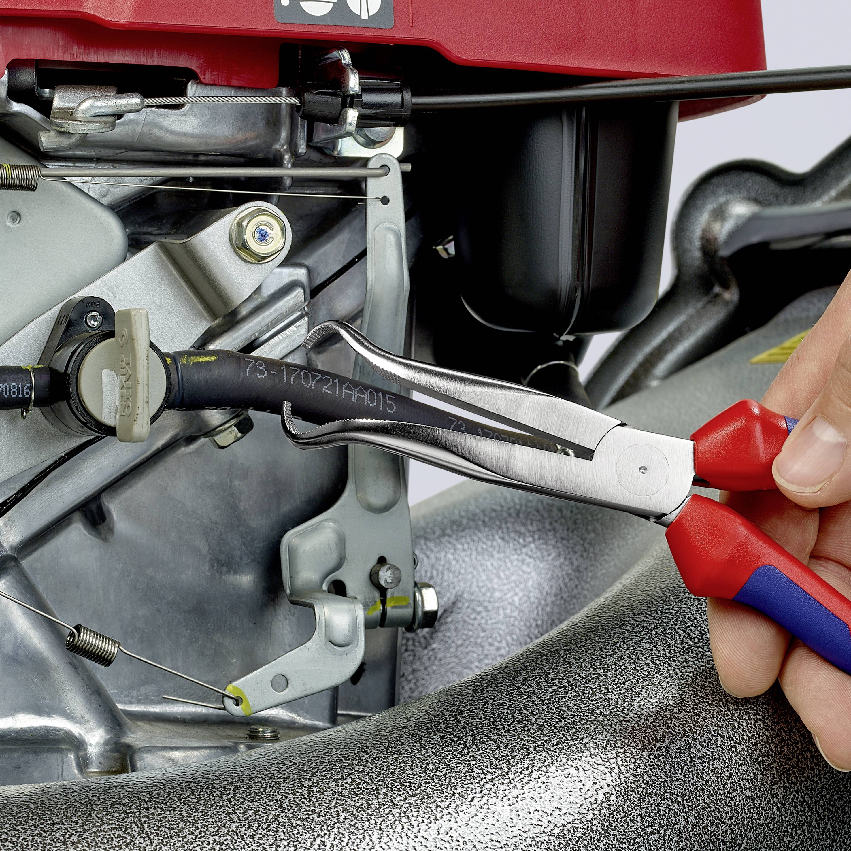 Een monteur gebruikt een tang om een metalen schroef aan een motor vast te draaien. De focus ligt op de hand en het gereedschap.