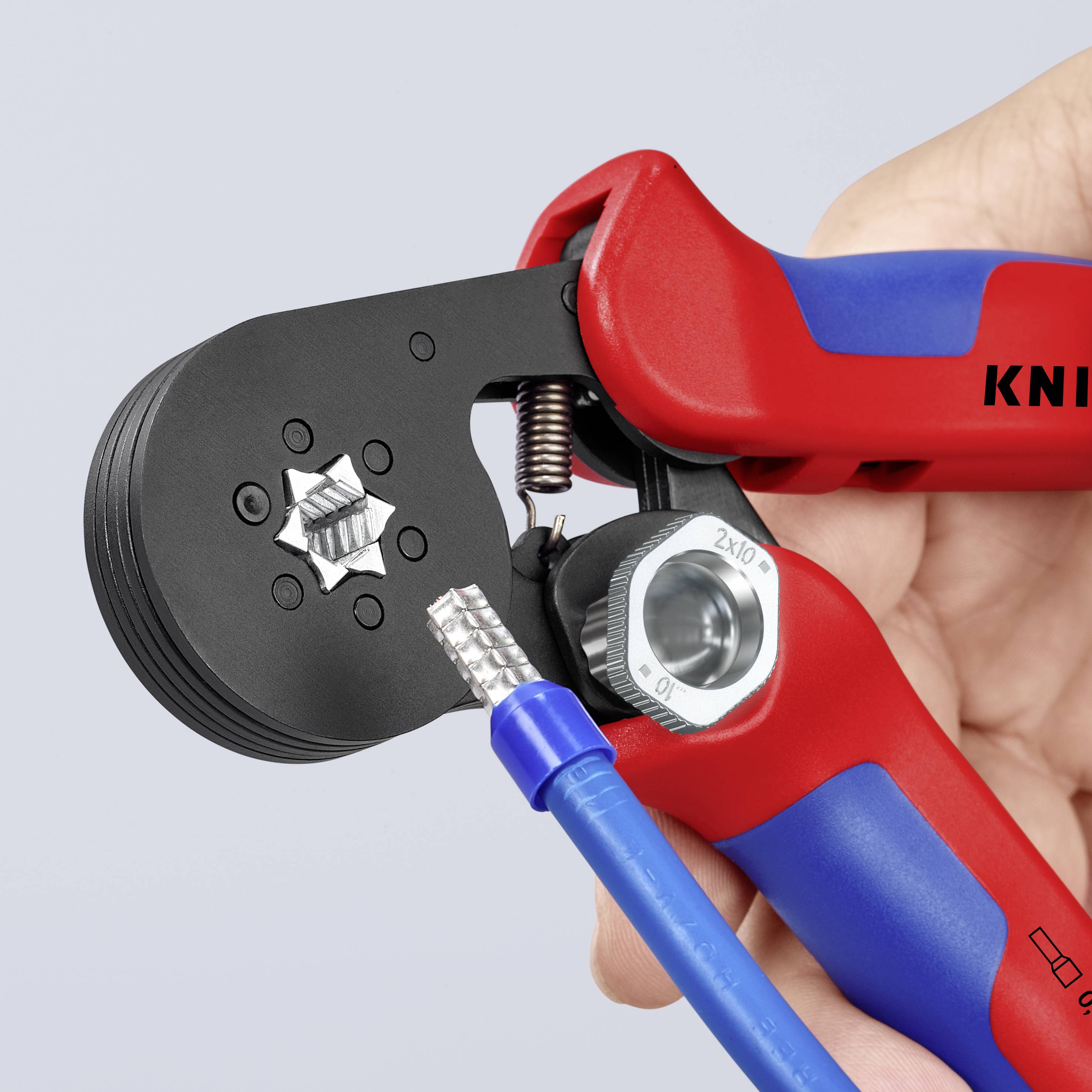 Een persoon houdt een krimptang vast die op het punt staat een elektrische kabel te bewerken. Het gereedschap vertoont de markering 'KNIP'.