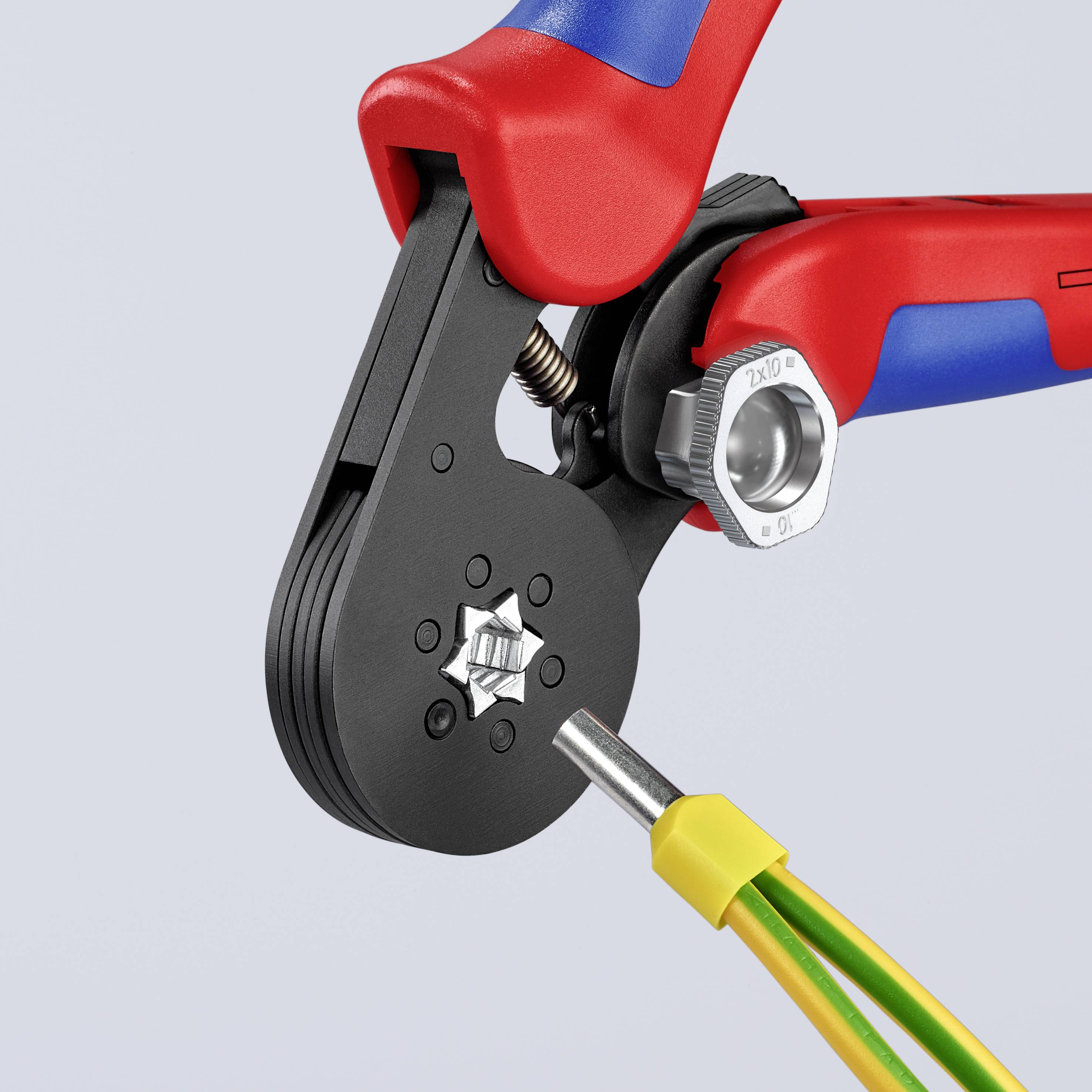 Een handgereedschap met een rode en blauwe greep klemt het uiteinde van een geel geïsoleerd kabel vast, geschikt voor elektrische werkzaamheden.