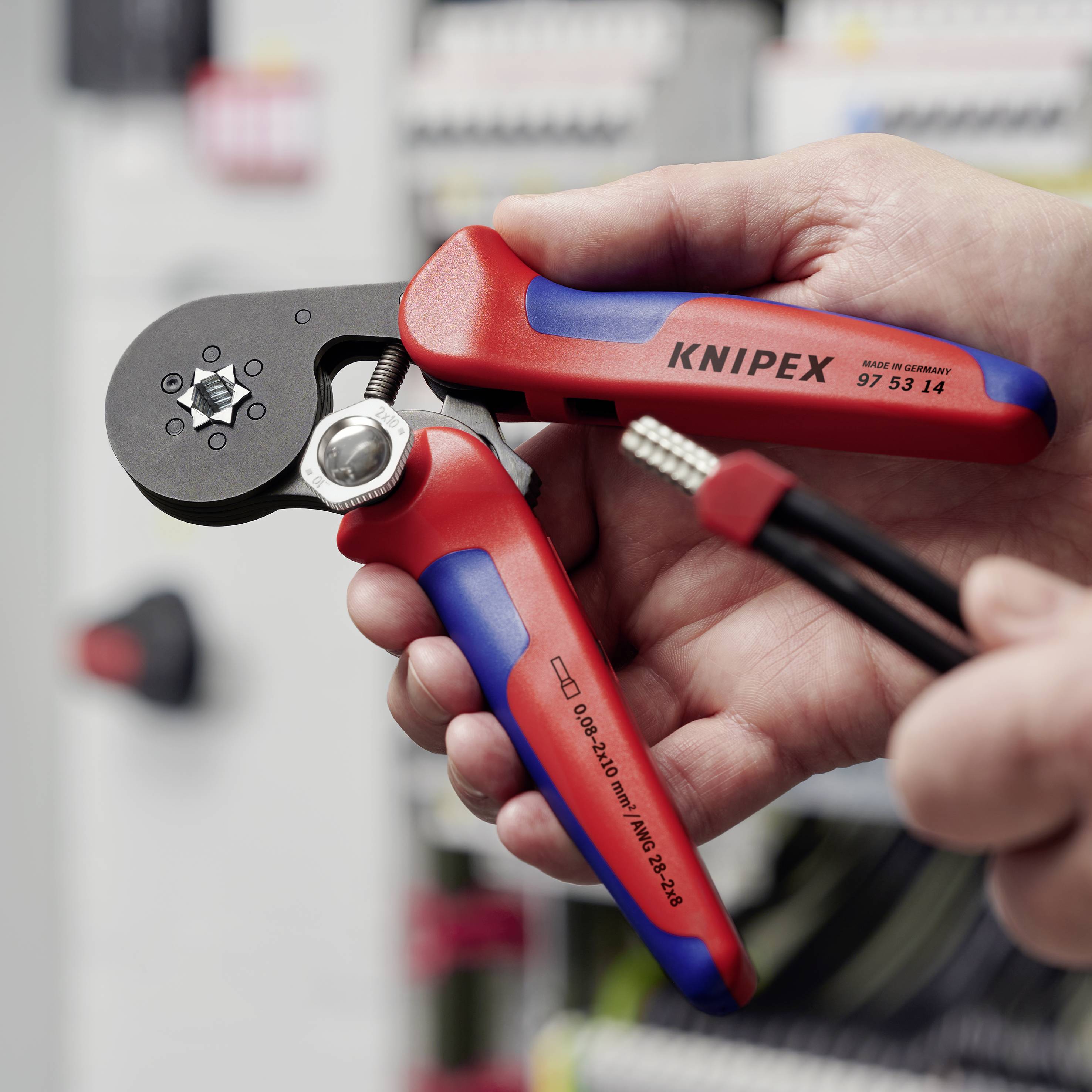 „Een paar rode krimptangen van het merk Knipex worden in de hand gehouden, klaar om een kabel te persen."