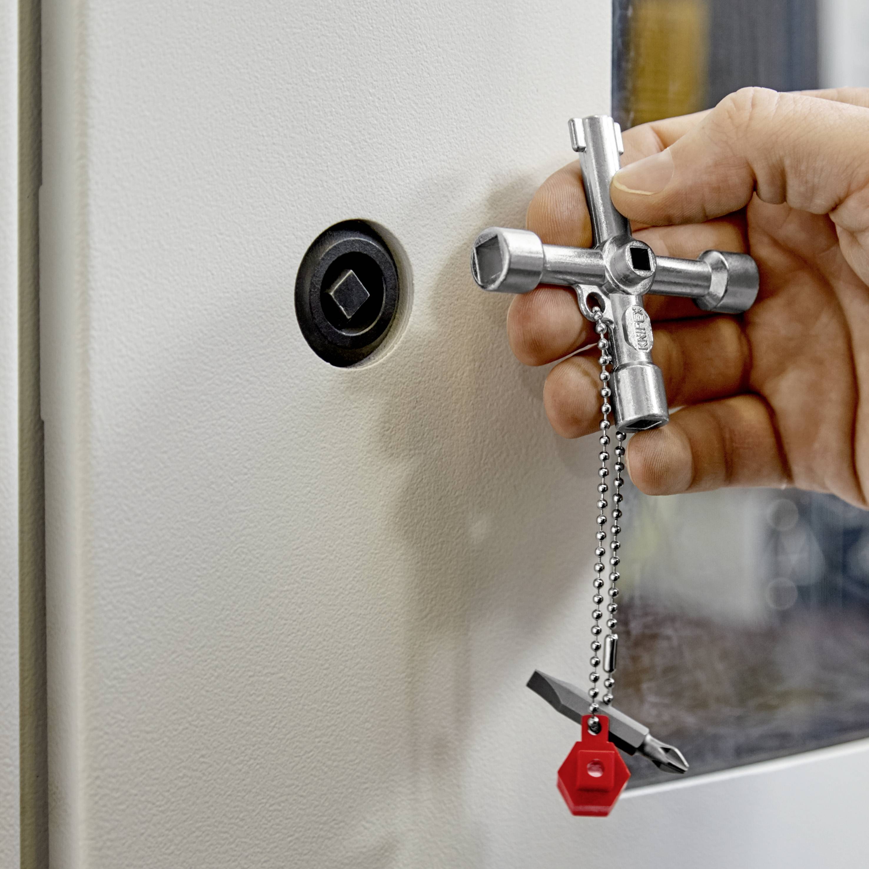 Een hand draait met een vierkante sleutel een slot aan een metalen deur.