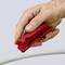 Een hand gebruikt een rood kabelkniptang om een wit kabel te bewerken.