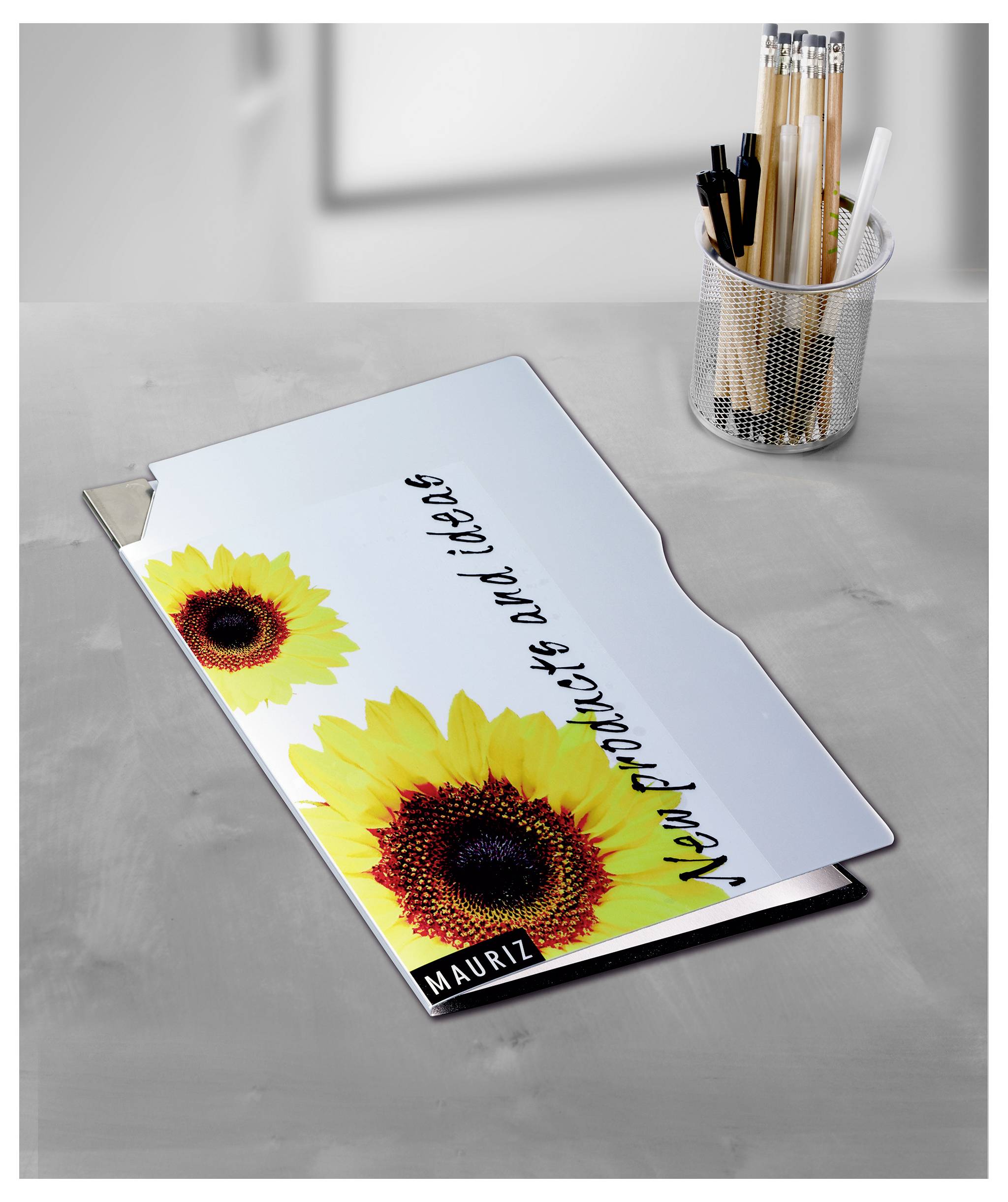 Gepersonaliseerde schooltas met zonnebloemmotief en naam 'Mauritz' op een grijze tafel naast een pennenhouder.