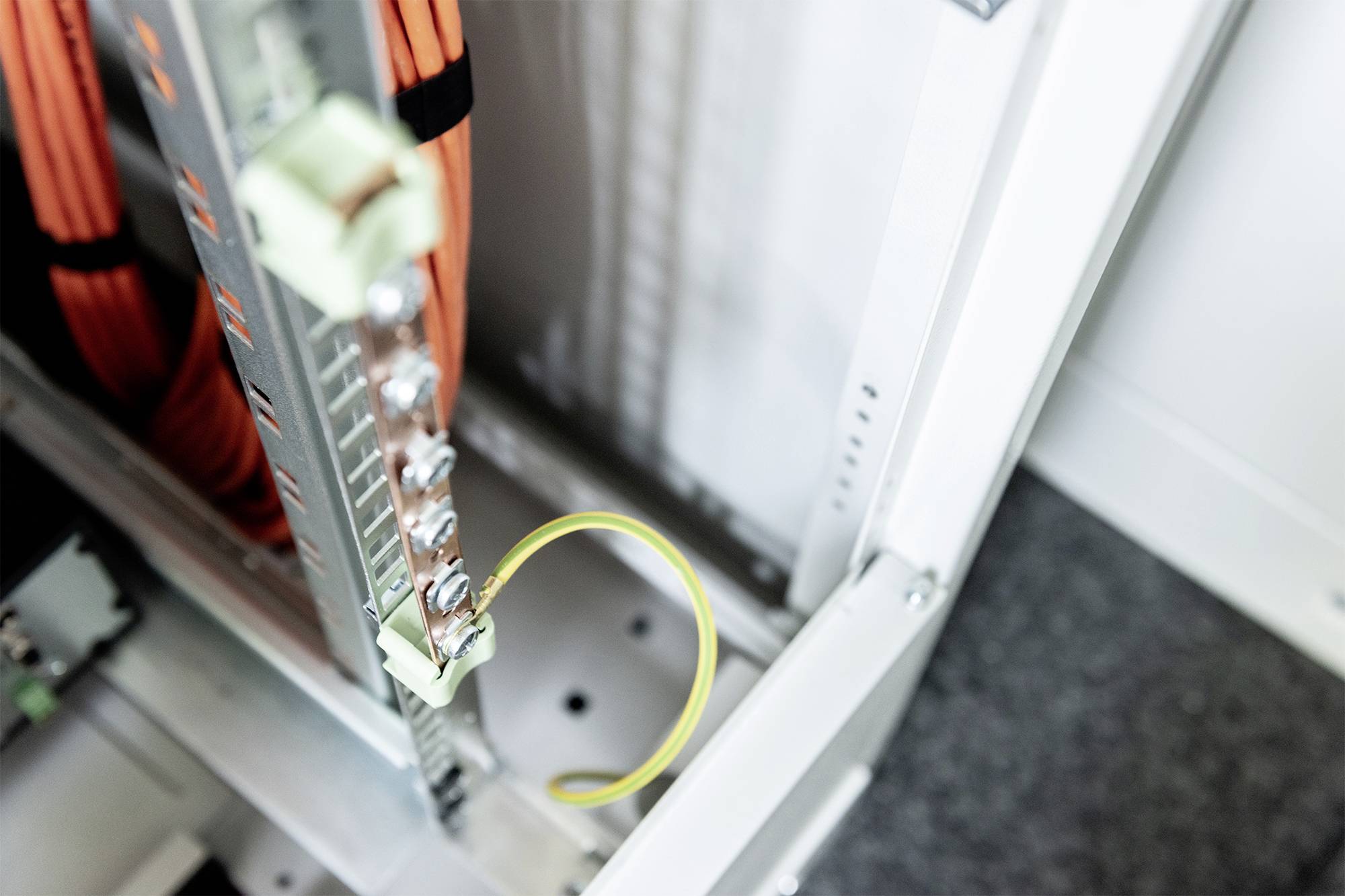 Een schakelkast met kabels toont een geel glasvezelkabel dat veilig is aangesloten op een verdeler, met focus op de kabelverbinding.