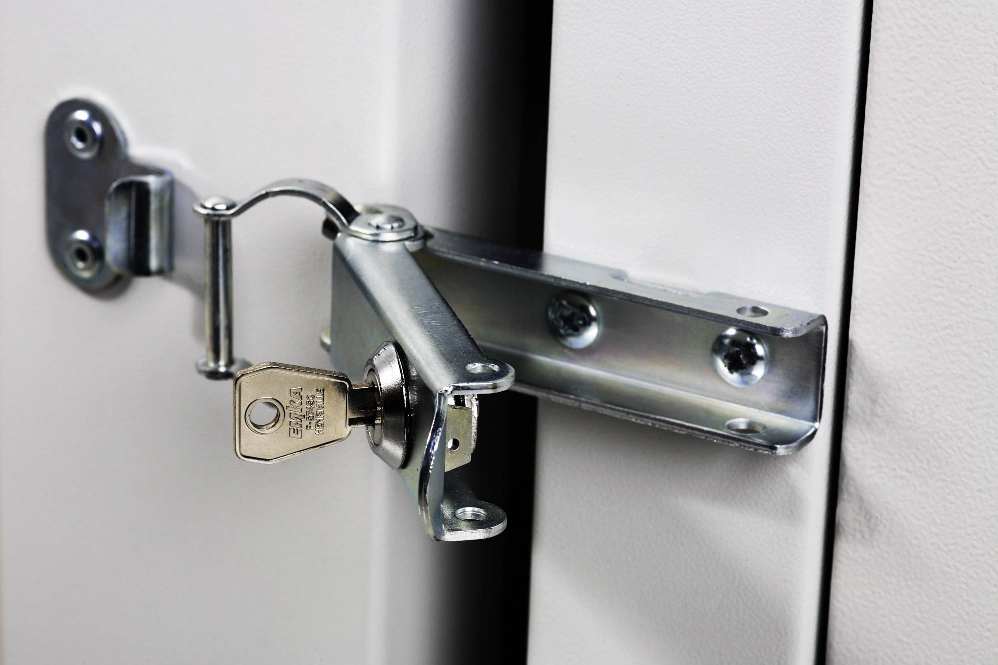 Sleutelslot aan een metalen deur, op slot. De sleutel steekt in het slot.