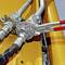 Pijptang grijpt metalen verbinding aan bij geel hydraulisch systeem. Gereedschap en componenten in focus, toont technische toepassing.