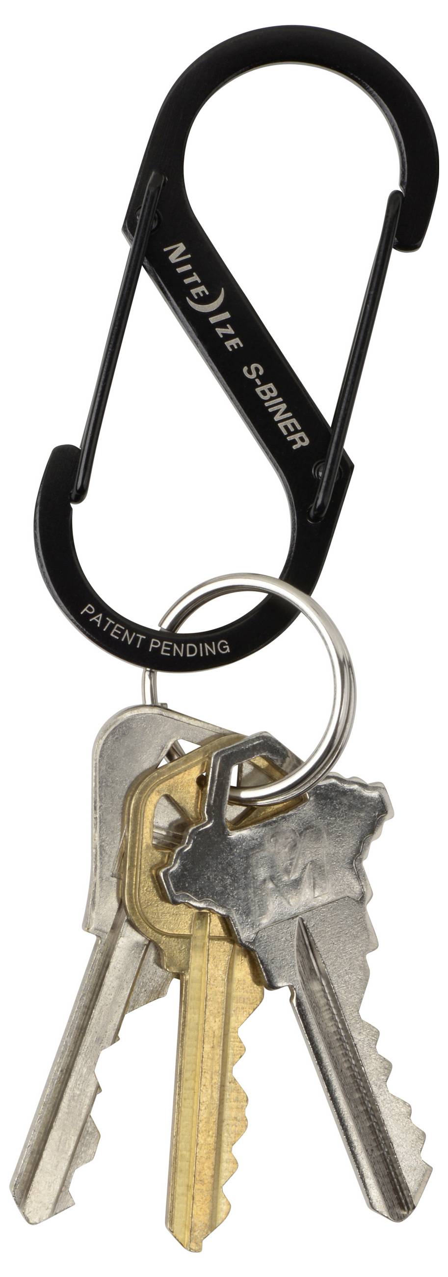 Een zwarte karabijnhaak sleutelhanger bevat verschillende metalen sleutels, waaronder een koperen sleutel en twee zilveren sleutels, verbonden door een klein metalen ringetje.