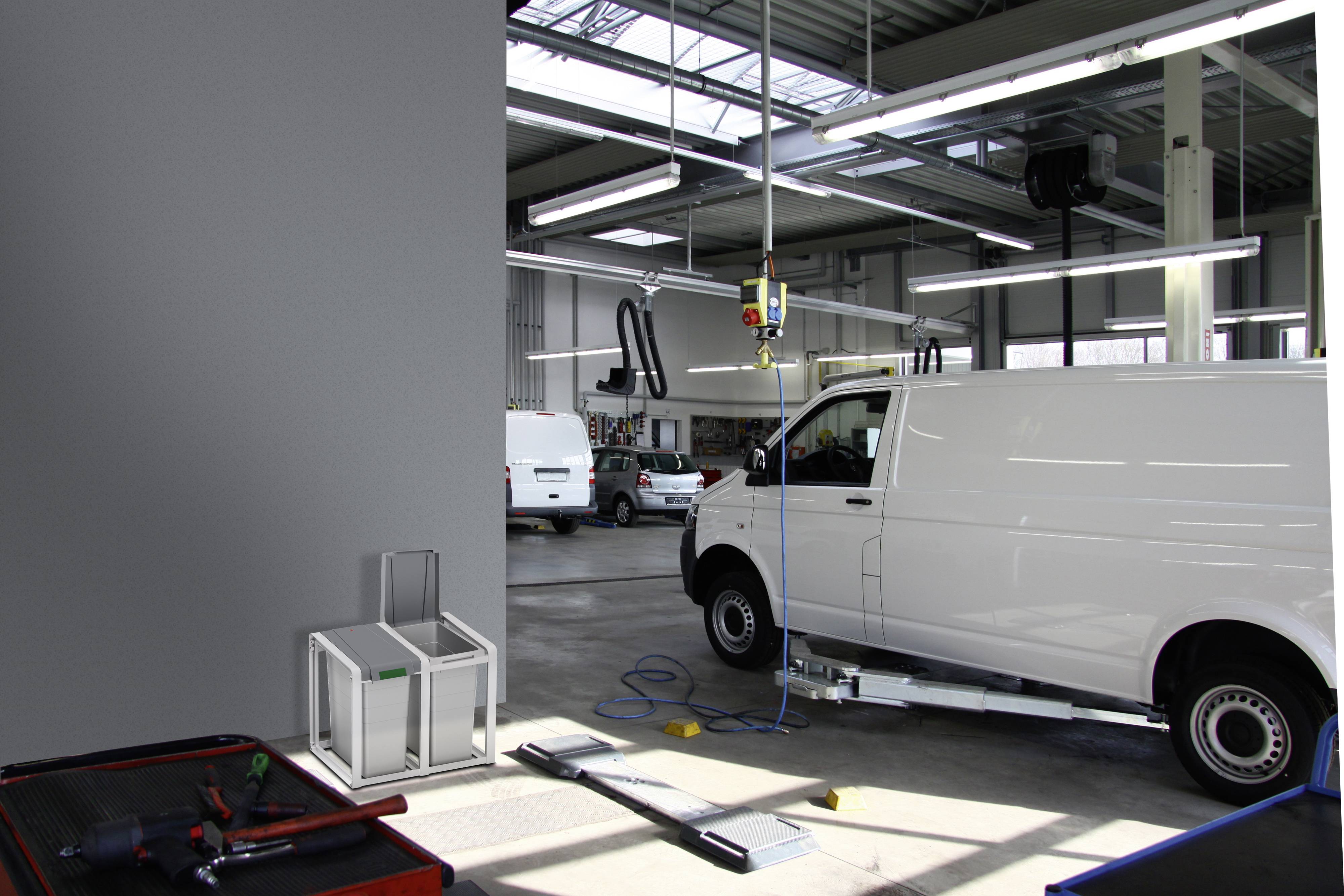 Een witte bestelwagen bevindt zich in een autogarage voor inspectie. Gereedschappen en apparatuur zijn op de achtergrond zichtbaar.