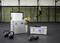 Kettlebells, dumbbells, and ropes on a fitness studio floor, with hanging rings and a person in motion in the background.